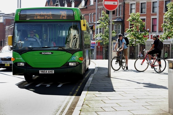 A green bus driving along a road