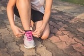 female tying a trainer shoelace on her run