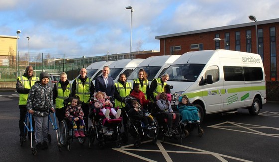 Children and carers standing alongside electric minibuses