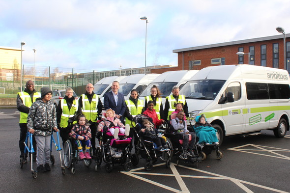 Wheelchair using children from Oakfield school and council workers in front of electric minibuses 