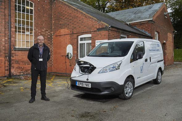 Man standing next to EV van charging