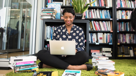 person sat on floor with books and laptop