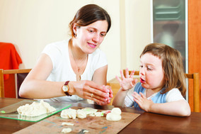 Mother and baby sculpting from clay at table