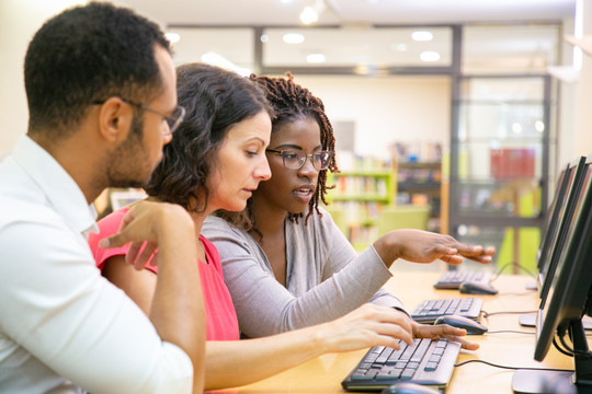 3 adults sat at a computer