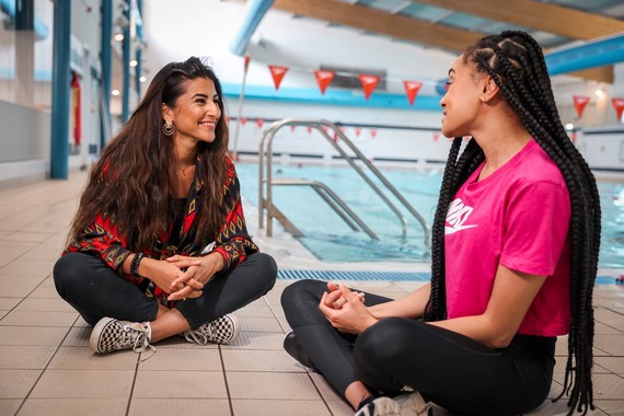 Summaya (left) and Olympian Alice Dearing (right) sat on the floor, poolside at Southglade Leisure Centre.