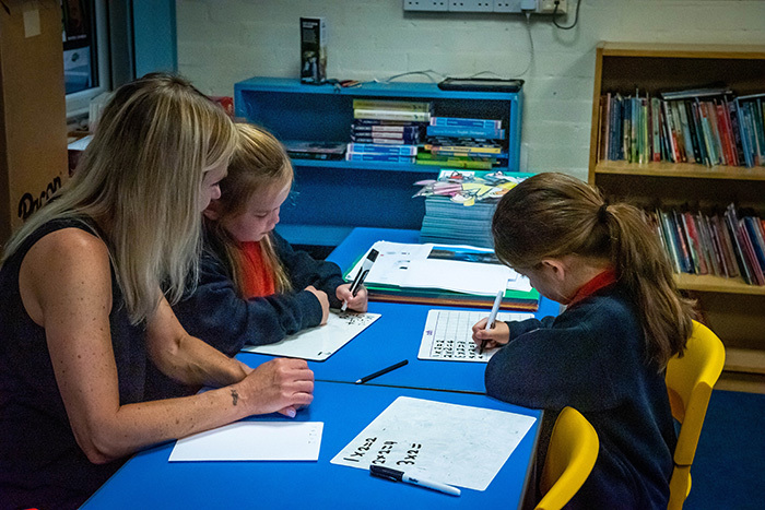 Students working at a desk with teacher at Ashfield Junior School in West Cumbria