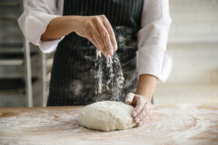 Baker dusting flour on dough