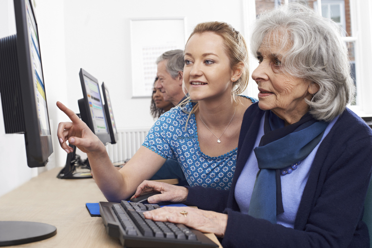Younger woman helping an older woman on a computer