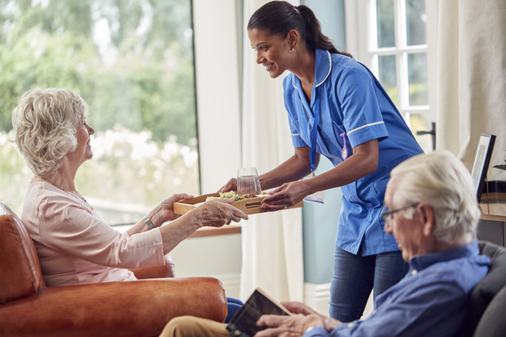 Care home assistant handing over food tray at lunch time