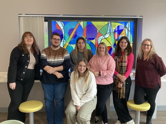 Students by a stained-glass window artwork