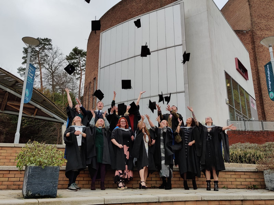 Clinical Associate Graduates in their gowns throwing hats into the air