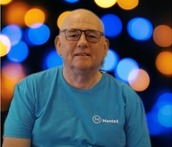 A white male wearing a blue t shirt with the logo mentell with a multicoloured background