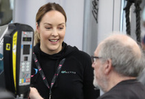 A female helping a man with the exercise machine