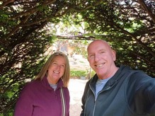 A male and female smiling at the camera whilst taking a selfie outside