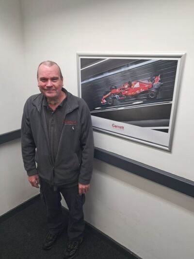 A man standing next to a framed picture of a car