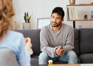 A woman sits on a sofa talking to a counsellor