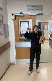 A lady holding a bunny toy and standing in a tracksuit in a hospital corridor