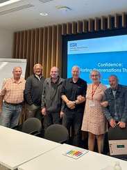 Six people smiling for a picture with a table in front of them