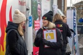 Volunteers from Cancer Research UK engaging with the public on a street, with promotional banners visible in the background.