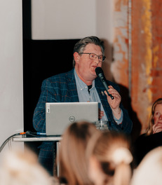 Picture of a man with a speakerphone presenting