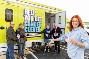 Four volunteers with leaflets in their hand pointing to a bright green van
