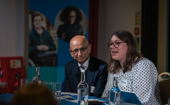 Two people on sitting at a table for a panel discussion