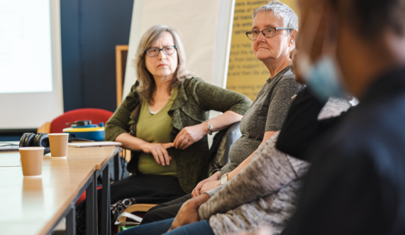 A group of people in a meeting room with coffee cups and flip chart paper