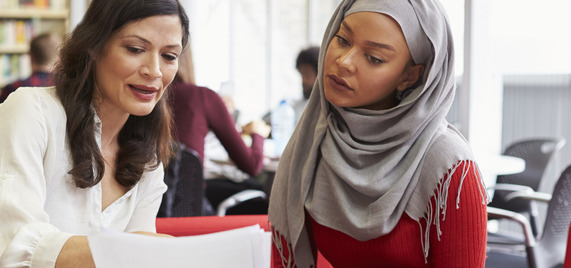 Two people working together, looking at a laptop
