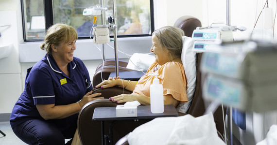 An MTW nurse looks towards a patient in a chair 