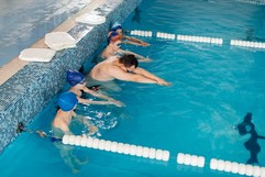 Kids being taught to swim by an instructor 
