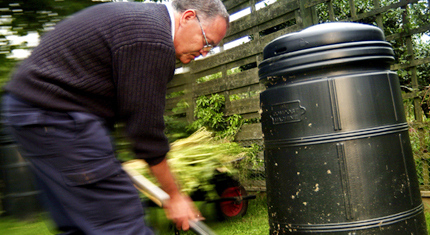 Man shovelling compost into a composter