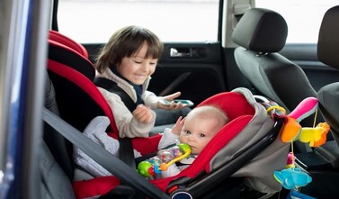 Baby and older brother in car seats. 