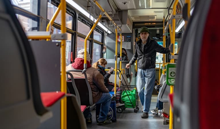 Photo of an elderly man walking through a bus
