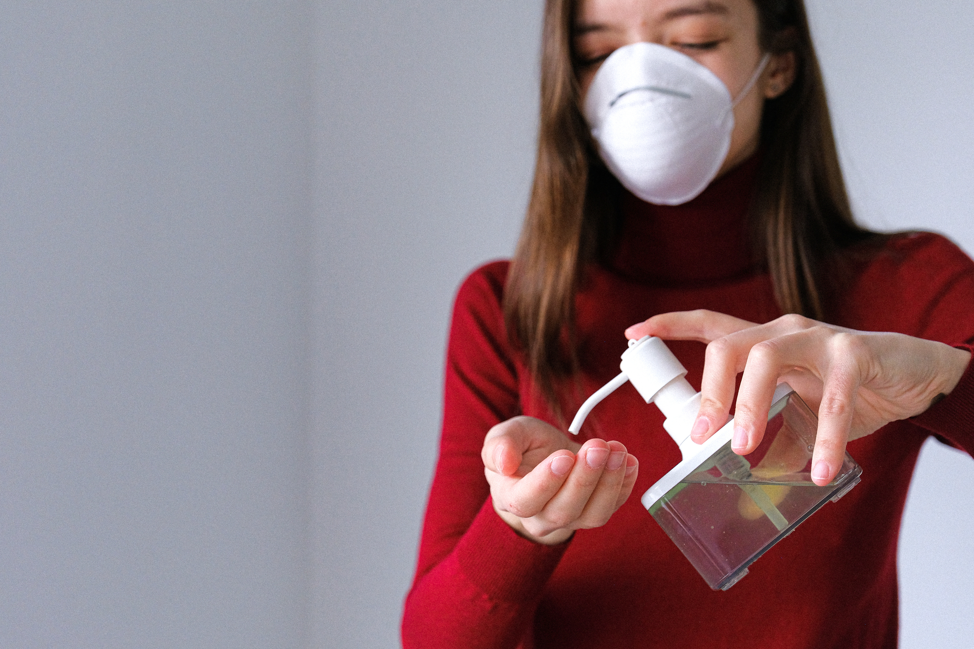 Woman wearing face mask applying hand sanitiser