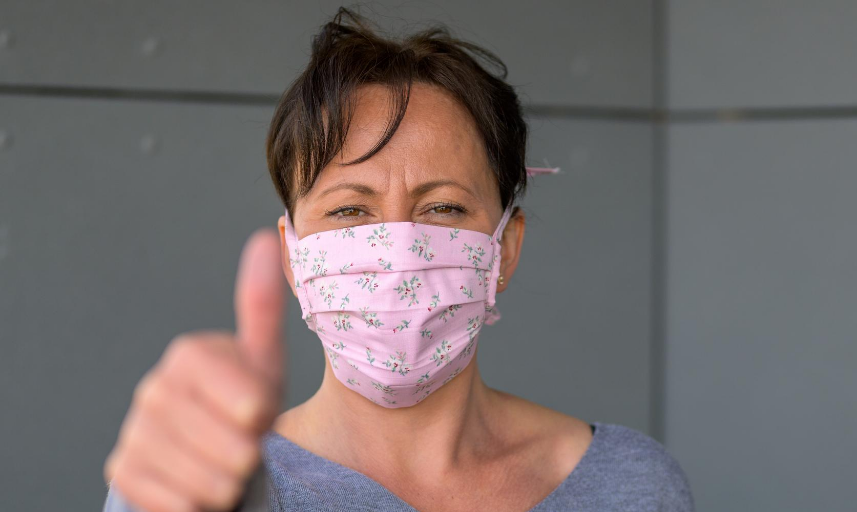 Woman wearing face mask giving thumbs up signal