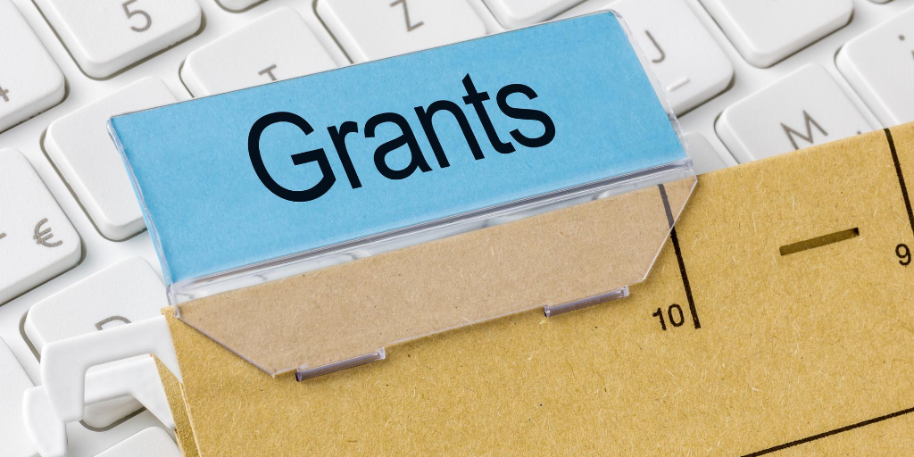 Computer keyboard with a manila folder on top labelled Grant