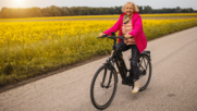 Woman riding electric bike past a field of yellow flowers