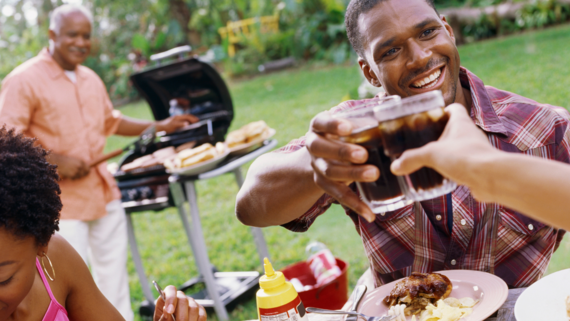 Man smiling, enjoying a drink at an outdoor BBQ party