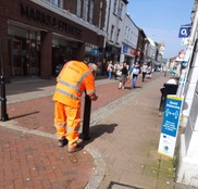 Man in orange high vis painting bollard in town centre
