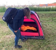 Member of the Outreach team looking into a tent