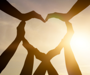 Hands forming heart shape with sun in the background