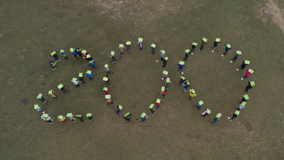 drone image showing birds-eye view of children making the shape of 200