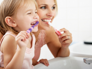 An adult and child brushing their teeth together