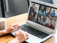 An online meeting with lots of smiling faces on a laptop screen