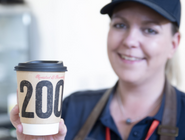 Smiling cafe worker holding a takeaway cup of coffee