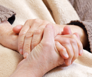 An older adult holding hands with another person