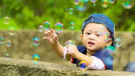 A toddler catching bubbles
