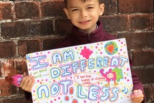 A child holding up a poster for Autistic Pride Day