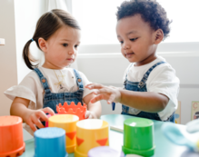 Two toddlers playing with colourful blocks