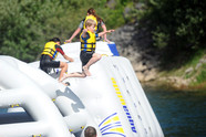 children jumping into the water, off large inflatables